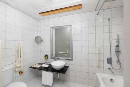 a white bathroom with a sink and a shower at Nina Hotel Causeway Bay in Hong Kong