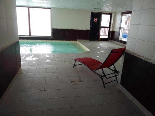 a swimming pool with a red chair in a building at Appartement dans residence de tourisme in Besse-et-Saint-Anastaise