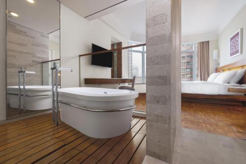 uma casa de banho com uma banheira, um lavatório e uma cama em Nina Hotel Causeway Bay em Hong Kong