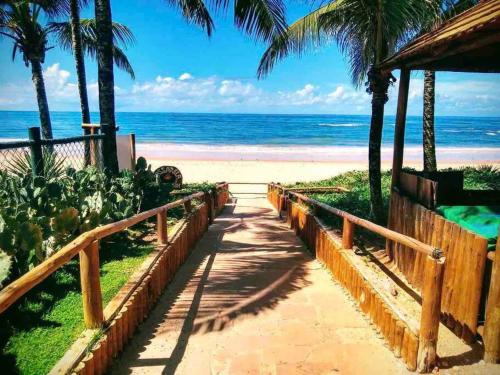a pathway to the beach with palm trees and the ocean at Seu cantinho no paraíso de Guarajuba - Bahia in Guarajuba