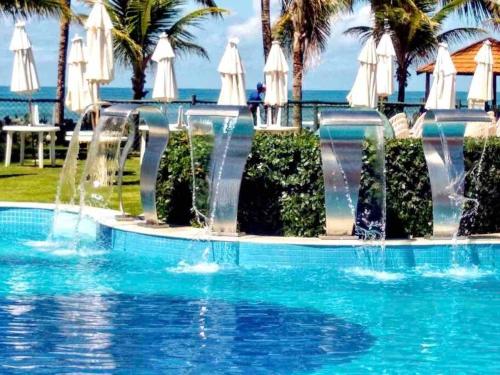 a swimming pool with water fountains in a resort at Seu cantinho no paraíso de Guarajuba - Bahia in Guarajuba