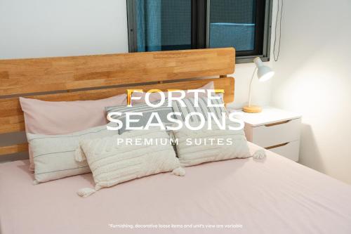 a white bed with a wooden headboard and pillows at Enclave Nature Suites @ Bukit Tinggi in Bentong