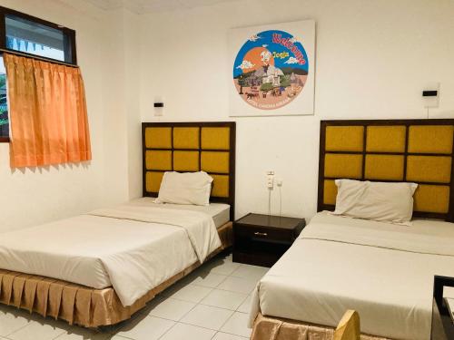 a room with two beds and a sign on the wall at Hotel Candra Kirana Syariah Prawirotaman Mitra RedDoorz in Yogyakarta