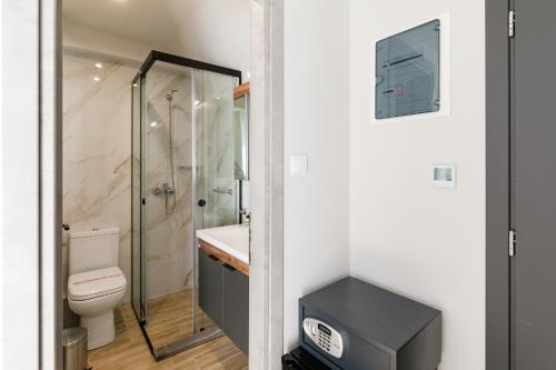 a bathroom with a toilet and a walk in shower at Comfort City Suites & Rooms in Larisa
