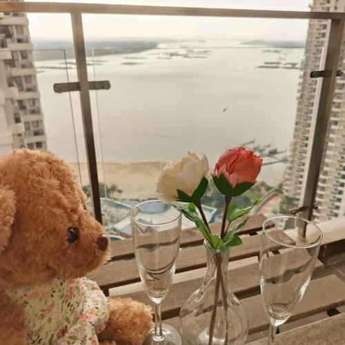 a teddy bear sitting on a table with two wine glasses at Bench/seaviews4-13pax/JohorBahru 9B amberside in Johor Bahru