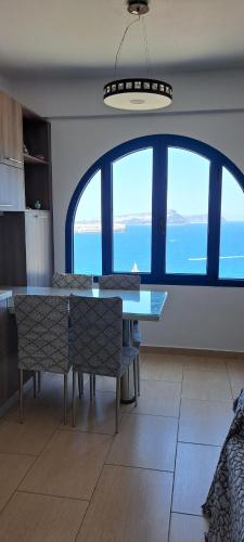 a dining room with a table and chairs and a large window at Caldera Heights Apartment in Akrotiri