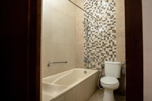 a bathroom with a toilet and a bath tub and a toilet at Oryza Hotel Malioboro in Sentool
