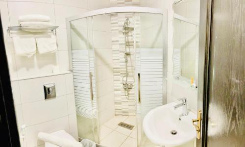 a white bathroom with a shower and a sink at Panorama Amman Hotel in Amman