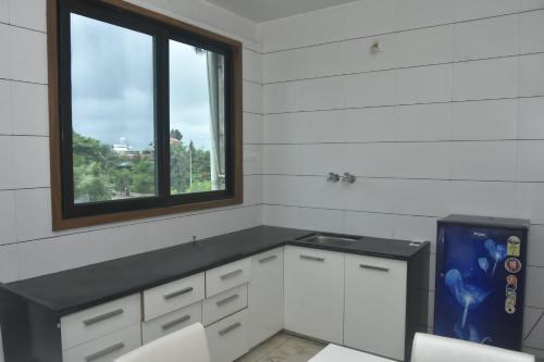 una cocina con armarios blancos y una ventana en Casa De Diu, en Diu