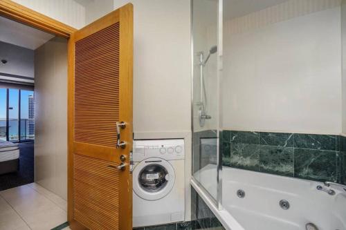 a bathroom with a washing machine and a bath tub at Deluxe Private Apartment and Studio - Ocean Views in Gold Coast