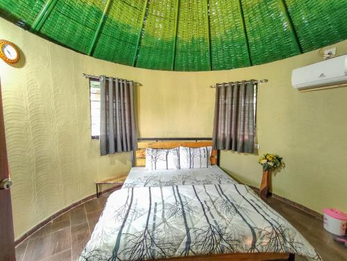- une chambre avec un lit et un plafond vert dans l'établissement Van Vagdo Resort, à Garudeshwar