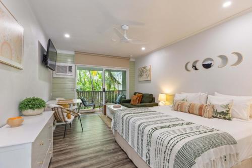 a bedroom with a large bed and a balcony at Tropic Retreat in Port Douglas