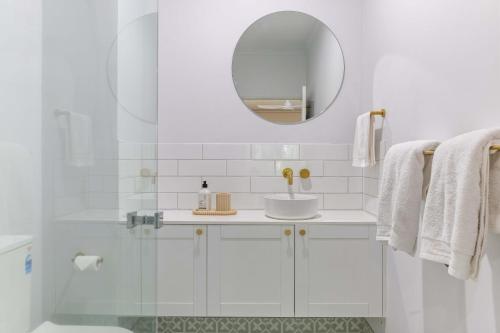 a white bathroom with a sink and a mirror at Tropic Retreat in Port Douglas