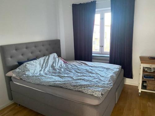 a bed in a bedroom with blue curtains and a window at Eurovision Finale 1BD in Malmö