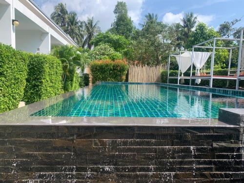 a swimming pool with a waterfall and a water feature at Phangan Hometown Resort - Adults Only in Baan Tai