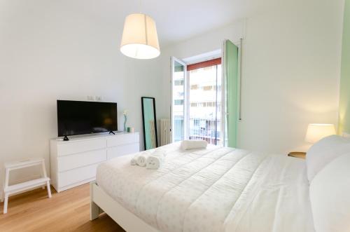 a white bedroom with a large bed and a tv at Vivimi Home Fiordalisi Stile & Comfort Vicino Metro in Milan
