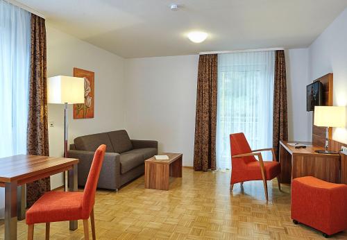 un soggiorno con divano, tavolo e sedie di Hotel & Residenz Am Kurpark a Schlangenbad