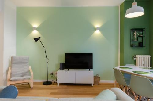 a living room with a television and a table with chairs at Vivimi Home Fiordalisi Stile & Comfort Vicino Metro in Milan