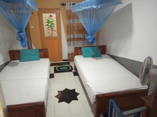 two beds in a room with blue curtains at Rohana Holiday Resort yala in Tissamaharama