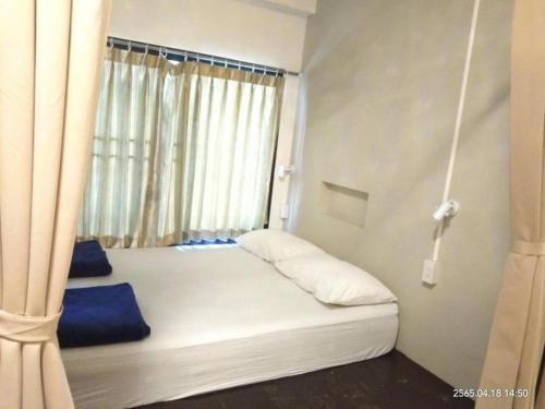 una cama en una habitación con ventana en Chiang Mai Happy House Hostel, en Chiang Mai