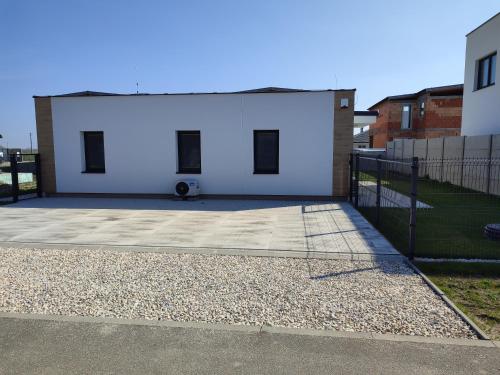 a white building with a fence in front of it at BÖJTÖS apartmány NESVADY in Nesvady