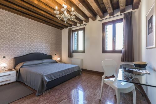 a bedroom with a bed and a desk and windows at Ca' Del Monastero 3 Collection Apartment for 4 Guests with Lift in Venice