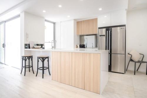 a kitchen with a refrigerator and some bar stools at Modern Seaside Oasis in Kings Beach in Caloundra