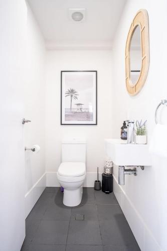 a white bathroom with a toilet and a sink at Modern Seaside Oasis in Kings Beach in Caloundra