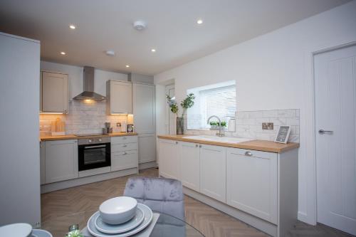 a kitchen with white cabinets and a glass table at Potterhouse Durham by #ShortStaysAway in Sheepscar