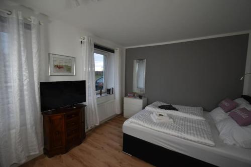 a bedroom with a bed and a flat screen tv at Ferienwohnung mit Boxspringbett in Behrensdorf