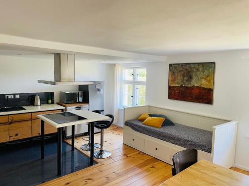 a room with a bed and a kitchen with a table at Lütt Oven Hus in Hiddensee