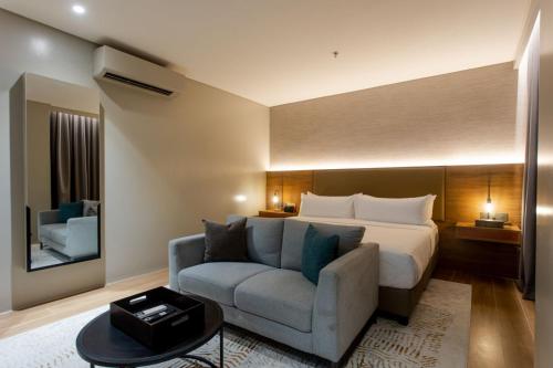 a hotel room with a bed and a couch at Brittany Hotel Villar City in Cavite