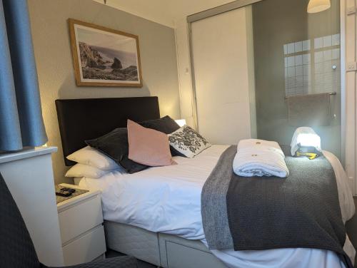 a bedroom with a bed with white sheets and pillows at En-suite nook near forest & sea, great value with fridge, microwave and TV in Lymington