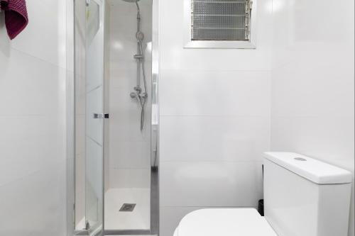 a white bathroom with a shower and a toilet at Barraca Breeze in Valencia