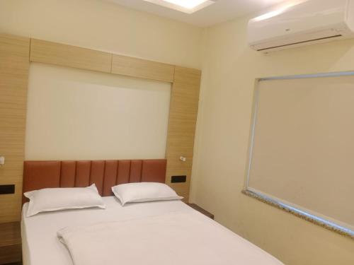 a bedroom with a bed with white sheets and a window at HOTEL SKYKING in Gauripur