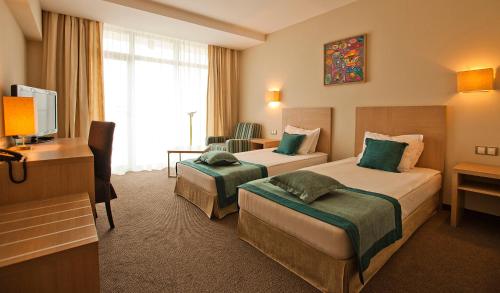 a hotel room with two beds and a desk at Azalia Beach Hotel Balneo & SPA in Saints Constantine and Helena