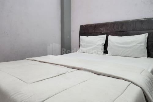 a large bed with white sheets and pillows at Puspita Homestay Mitra RedDoorz in Jakarta