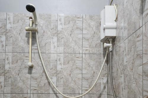 a shower with a hose attached to a wall at Puspita Homestay Mitra RedDoorz in Jakarta