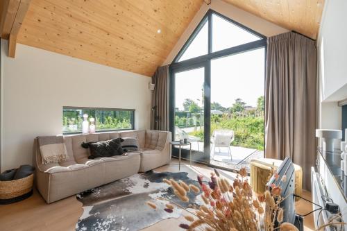 a living room with a couch and a large window at Riethoek Westerschouwen in Burgh Haamstede