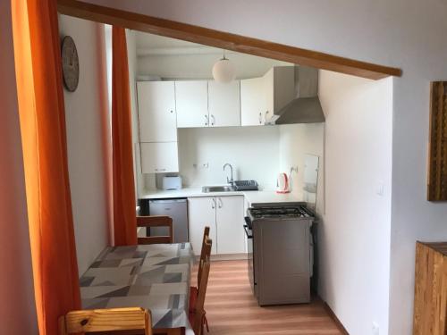 a kitchen with white cabinets and a table and a stove at Vila Lomnička in Vysoke Tatry - Tatranska Lomnica.