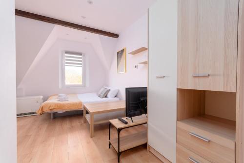 a small bedroom with a bed and a television at Groszowa Comfort Studio in Jelenia Góra