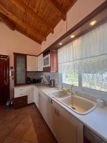 a kitchen with a sink and a large window at Ermioni Sea View Villa in Ermioni