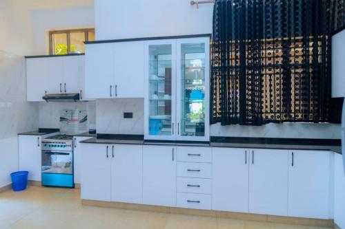 eine Küche mit weißen Schränken und einem Glaskühlschrank in der Unterkunft Douglas Home in Ruhengeri