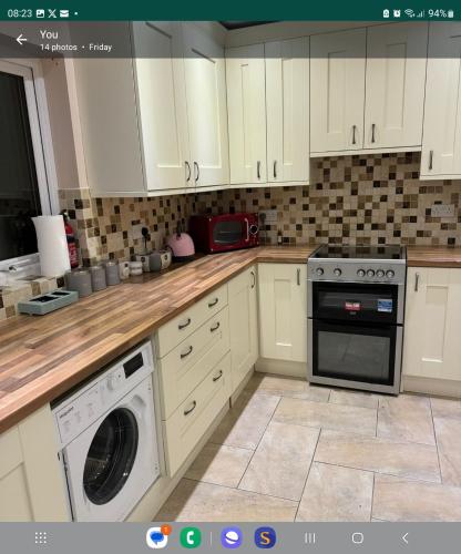 a kitchen with white cabinets and a washer and dryer at detached house neat in Wellingborough