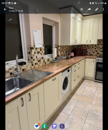 cocina con armarios blancos, fregadero y lavavajillas en detached house neat, en Wellingborough