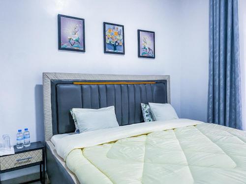 ein Bett in einem Schlafzimmer mit drei Bildern an der Wand in der Unterkunft Douglas Home in Ruhengeri