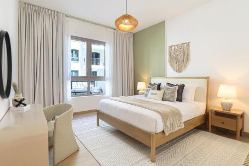 a bedroom with a bed and a desk and a window at HiGuests - Luxurious Boho Beach 2BR Apartment in La Mer in Dubai