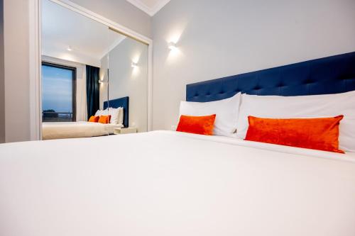 a bedroom with a large white bed with red pillows at Urban by CityBlue Hotel, Dar es Salaam in Dar es Salaam