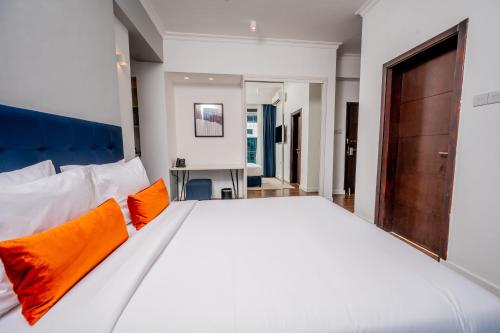 a bedroom with a large white bed with orange pillows at Urban by CityBlue Hotel, Dar es Salaam in Dar es Salaam