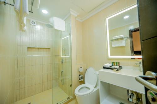 a bathroom with a shower and a toilet and a sink at Urban by CityBlue, Dar es Salaam in Dar es Salaam